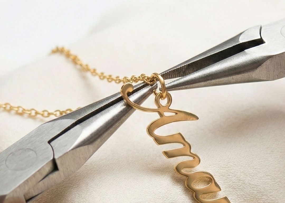 Hands using pliers to assemble a personalized gold name necklace