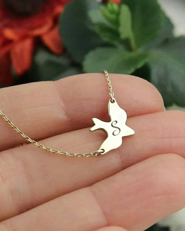 Gold necklace with a dove-shaped pendant on a hand against a blurred background - CG2028S,CG2030S,CG2032S