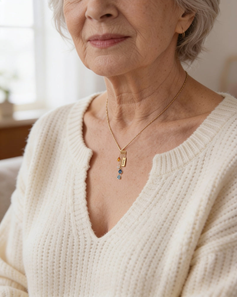 Grandmother wearing a dainty gold cascading birthstone necklace with a small Nana tag at the collarbone