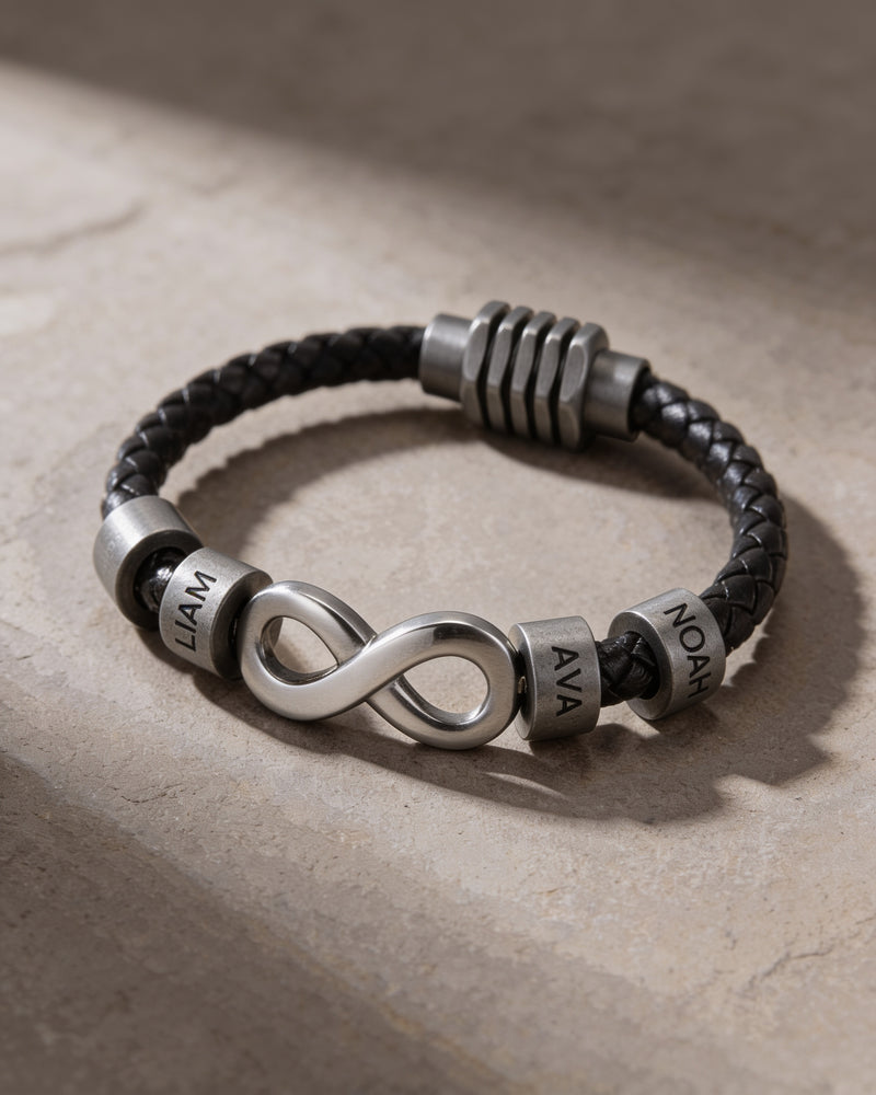 Close-up of the silver infinity link and engraved name beads on braided black leather